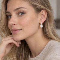 Sterling silver pearl huggie earrings worn on ear