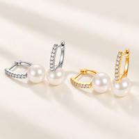 Freshwater pearl huggie earrings in sterling silver on white background