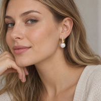 Sterling silver pearl huggie earrings worn on ear